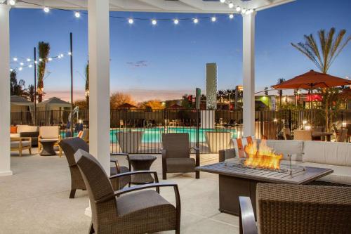 a patio area with chairs, tables, chairs, and umbrellas at Cambria Hotel Phoenix Chandler - Fashion Center in Chandler