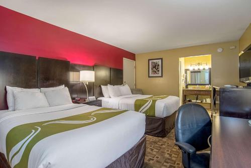 a hotel room with two beds and a desk at Quality Inn & Suites Phoenix NW - Sun City in Youngtown