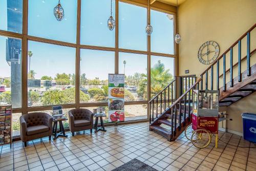 a lobby with a staircase and a clock in a building at Quality Inn & Suites Phoenix NW - Sun City in Youngtown