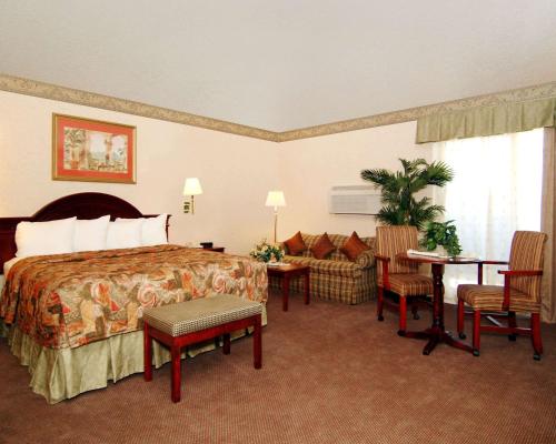 サニーベールにあるクオリティ イン サンタ クララ コンベンション センターのベッド、テーブル、椅子が備わるホテルルームです。