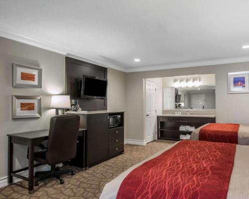 a hotel room with a bed and a desk with a computer at Quality Inn Downey in Downey