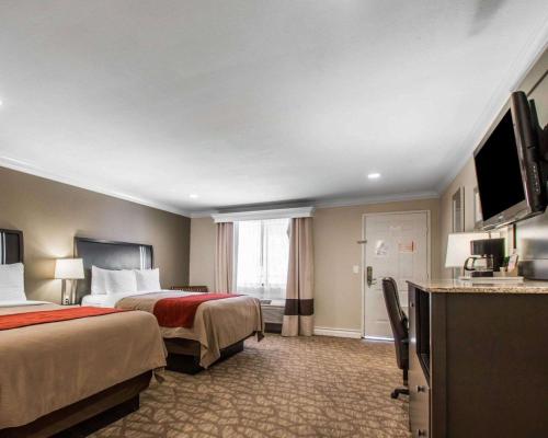 a hotel room with two beds and a flat screen tv at Quality Inn Downey in Downey