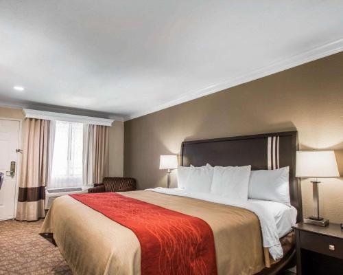 a hotel room with a large bed with a red blanket at Quality Inn Downey in Downey