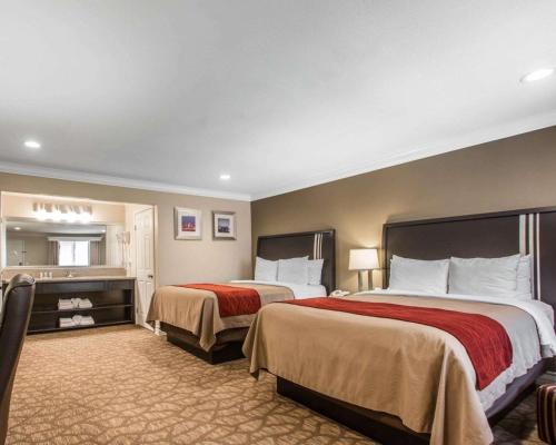 a hotel room with two beds and a mirror at Quality Inn Downey in Downey