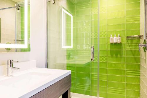 a green tiled bathroom with a sink and a shower at Rodeway Inn near Melrose Ave in Los Angeles