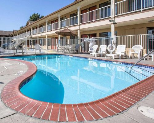 une grande piscine dans un hôtel avec des chaises et des tables dans l'établissement Quality Inn & Suites Woodland - Sacramento Airport, à Woodland
