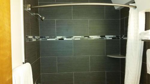 a bathroom with a shower with black tiles at Rodeway Inn Civic Center in San Francisco