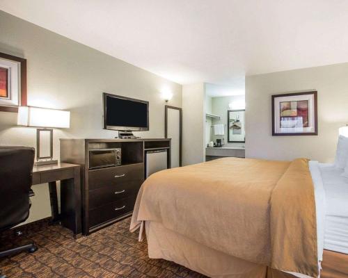 a hotel room with a bed and a desk with a television at Quality Inn & Suites Woodland - Sacramento Airport in Woodland