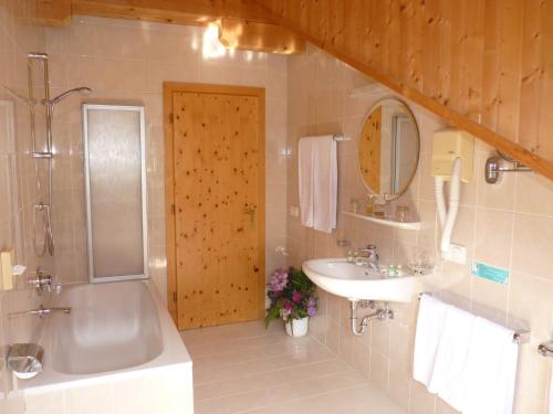 La salle de bains est pourvue d'une baignoire, d'un lavabo et d'une douche. dans l'établissement Hotel Fortuna, à Ortisei