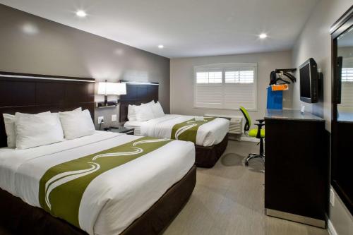 a hotel room with two beds and a desk at Bay Area Inn & Suites in Hayward