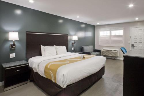 a hotel room with a large bed and a chair at Bay Area Inn & Suites in Hayward