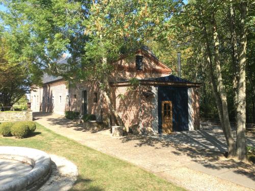 an old brick building in a yard with trees at Les Confidences de Messire Sanglier, stylished guest houses in Beauraing