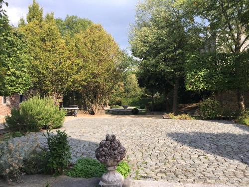a garden with a statue in the middle of a courtyard at Les Confidences de Messire Sanglier, stylished guest houses in Beauraing