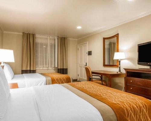 a hotel room with two beds and a desk and a television at Blu Pacific Hotel in Monterey