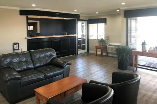a living room with a leather couch and a table at Rodeway Inn Ontario Mills Mall in Guasti