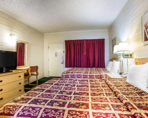 a hotel room with a large bed with a red curtain at Jefferson Inn in Yreka
