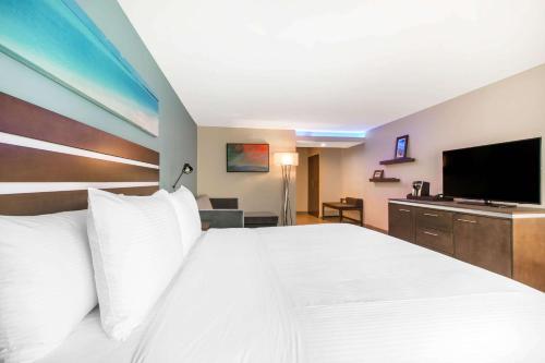 a hotel room with a large bed and a flat screen tv at The Cove Hotel in Long Beach