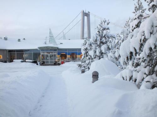 a building covered in snow with a bridge in the background at Hotell Höga Kusten in Sandöverken
