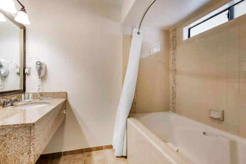 a bathroom with a tub and a sink and a mirror at Quality Inn Fallbrook I-15 in Fallbrook