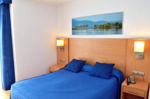 ein Schlafzimmer mit einem blauen Bett mit blauen Kissen in der Unterkunft Hotel del Port in Sant Carles de la Ràpita