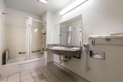 a bathroom with a sink and a tub and a mirror at Rodeway Inn Beaumont in Beaumont