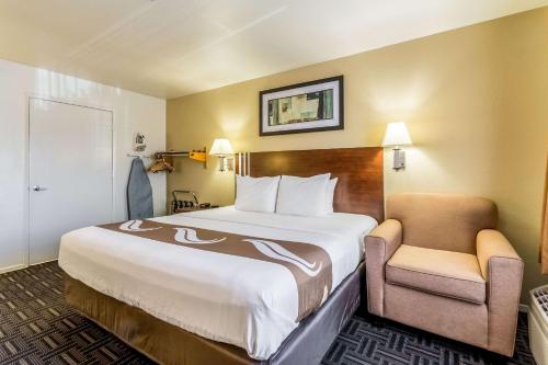 una habitación de hotel con una cama grande y una silla en Quality Inn Fresno Near University, en Fresno