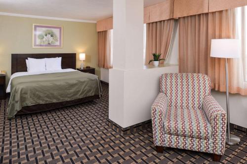 Quality Inn & Suites Montebello - Los Angeles في مونتيبيلو: غرفه فندقيه بسرير وكرسي