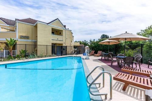 - une piscine avec des tables et des chaises à côté d'un bâtiment dans l'établissement Quality Inn & Suites Capitola, à Capitola