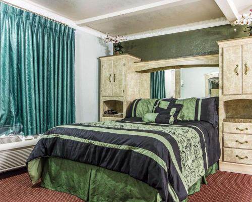 1 dormitorio con cama y cortinas verdes en Rodeway Inn Chico University Area, en Chico
