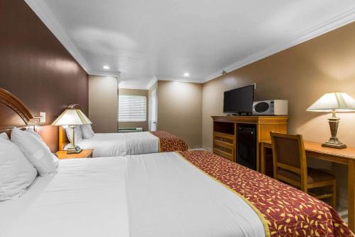 Habitación de hotel con 2 camas y escritorio en Rodeway Inn Cypress, en Cypress
