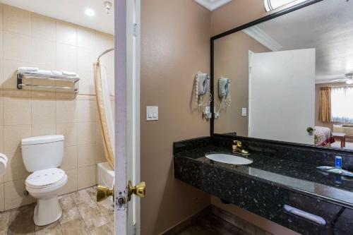 a bathroom with a toilet and a sink and a mirror at Rodeway Inn Cypress in Cypress