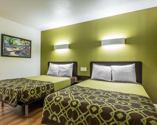 two beds in a small room with green walls at Rodeway Inn Downtown Hanford in Hanford