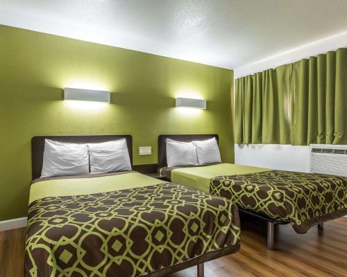 two beds in a small room with green walls at Rodeway Inn Downtown Hanford in Hanford