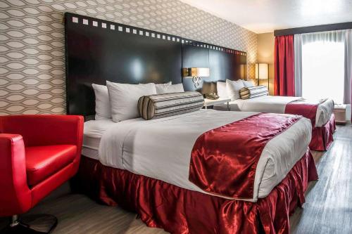 ロサンゼルスにあるTilt Hotel Universal/Hollywood, Ascend Hotel Collectionのベッド2台と赤い椅子が備わるホテルルームです。