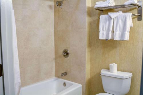 a bathroom with a toilet and a shower with towels at Tilt Hotel Universal/Hollywood, Ascend Hotel Collection in Los Angeles