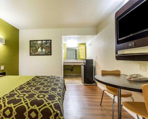 a hotel room with a bed and a table and a television at Rodeway Inn Downtown Hanford in Hanford