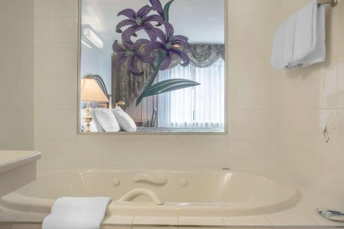 Baño blanco con bañera y espejo en Rodeway Inn Fallsview, en Niagara Falls