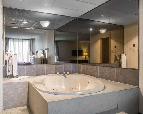 uma grande banheira numa casa de banho com um espelho grande em Quality Hotel & Suites Woodstock em Woodstock