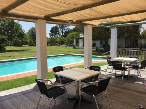 un patio con mesas y sillas junto a una piscina en Blue Skies Country House, en Lorraine