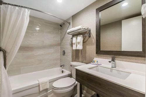 a bathroom with a toilet and a sink and a bath tub at Comfort Inn Barrie in Barrie