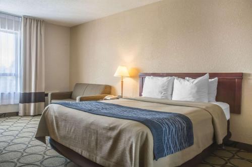 a hotel room with a large bed and a chair at Comfort Inn London - Ontario in London