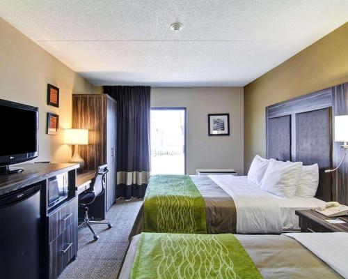 a hotel room with two beds and a flat screen tv at Comfort Inn St. Catharines Niagara in St. Catharines