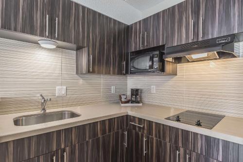a kitchen with wooden cabinets and a sink and a microwave at Comfort Inn Trenton in Trenton