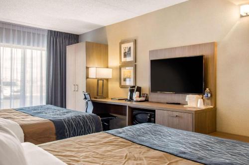 a hotel room with two beds and a flat screen tv at Comfort Inn Airport Dorval in Dorval