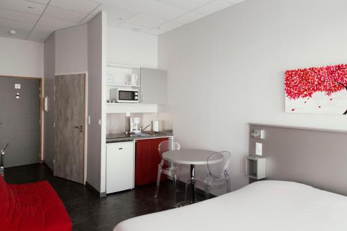 a room with a bed and a table and a kitchen at Smartappart Lorient in Lorient