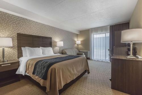 a hotel room with a large bed and a chair at Comfort Inn Levis in Lévis