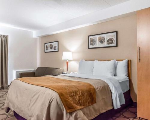 a hotel room with a large bed and a chair at Comfort Inn Riviere-du-Loup in Rivière-du-Loup