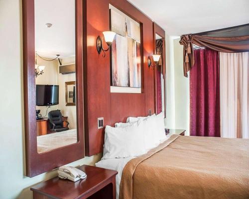Habitación de hotel con cama y espejo en Quality Hotel Fallsview Cascade, en Niagara Falls