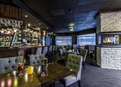 Un restaurante con una mesa y sillas y un bar. en Quality Inn & Suites, en Matane