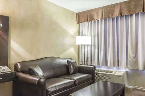 a living room with a leather couch and a table at Quality Hotel & Conference Centre in Campbellton